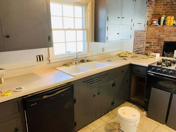 Jonesboro house for rent - a kitchen with gray cabinets and a sink and a window