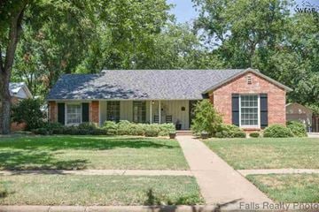 Wichita Falls house for rent - A house with a brick facade and a grey roof is surrounded by greenery.