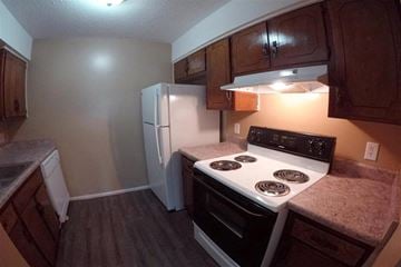 Olathe apartment for rent - A kitchen with a stove top oven and a refrigerator.