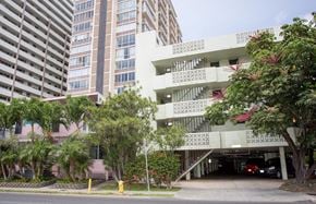 Honolulu apartment for rent - A white building with a red roof is in front of a taller building.