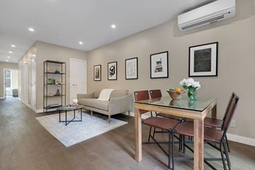 Ny apartment for rent - A modern living room with a glass table and chairs, a sofa, and framed pictures on the wall.