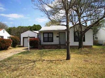 Wichita Falls house for rent - A small white house with a porch and a tree in front.