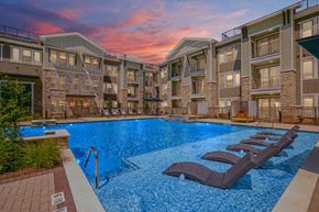 Northlake apartment for rent - an apartment pool with two lounge chairs in front of an apartment building
