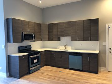 Chicago apartment for rent - a kitchen with dark cabinets and a stove and a sink