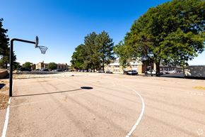 Pueblo apartment for rent - an empty basketball court in a parking lot with trees