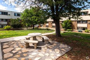 Pueblo apartment for rent - a picnic table sitting under a tree in front of an apartment building