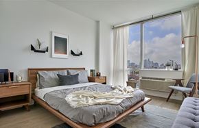 Hoboken apartment for rent - A bedroom with a large bed and a view of the city.
