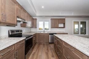 Portage La Prairie apartment for rent - a large kitchen with marble counter tops and wooden cabinets