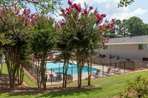 Fairburn apartment for rent - A pool surrounded by trees with pink flowers.