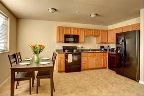 Watford City apartment for rent - a kitchen with wooden cabinets and a table with chairs
