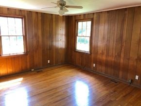 Talladega house for rent - an empty room with wooden floors and a ceiling fan