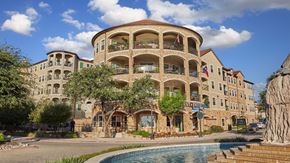 Mckinney apartment for rent - Looking from across the street at the rotunda part of the Bell Tower Flats apartment building. There are trees in front and the sky is partially cloudy.
