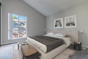 Riverside apartment for rent - A bedroom with a large bed and a view of the beach through the window.