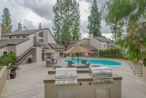 Riverside apartment for rent - A backyard with a pool, grill, and patio furniture.