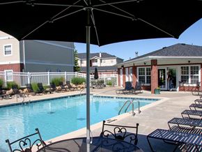 O'fallon apartment for rent - a swimming pool with chairs and umbrellas next to a building