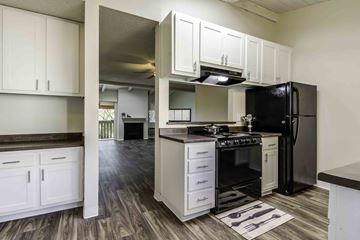 El Cajon apartment for rent - A kitchen with black appliances and white cabinets.