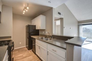 Santa Clarita apartment for rent - A kitchen with a black refrigerator and white cabinets.