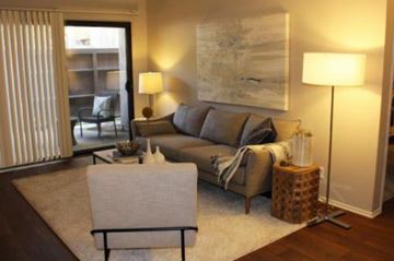Riverside apartment for rent - A living room with a grey couch, a white chair, and a large painting on the wall.