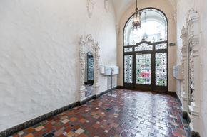San Francisco apartment for rent - A hallway with a tiled floor and a large arched doorway with an "EXIT" sign above it.