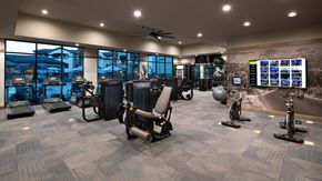 Tucson apartment for rent - a spacious fitness center with cardio equipment and a large window