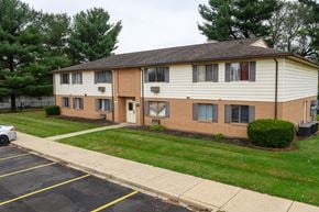 Canton apartment for rent - a white and brick apartment building with a lawn and trees