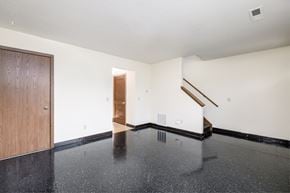 Canton apartment for rent - an empty living room with white walls and black flooring and a wooden door