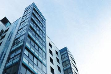 Brooklyn apartment for rent - A tall building with many windows is seen against a blue sky.