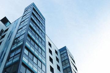 Riverdale apartment for rent - A tall building with many windows is seen against a blue sky.