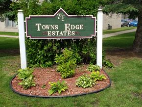 Glencoe apartment for rent - a sign for the towns edge estates in front of a garden