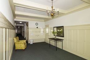 San Francisco apartment for rent - A yellow chair sits in a room with a chandelier and a painting on the wall.