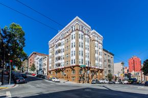San Francisco apartment for rent - A large white building with a red roof is in the middle of a street.