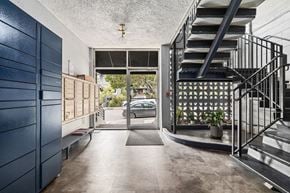 Oakland apartment for rent - A modern house entrance with a staircase and a glass door.