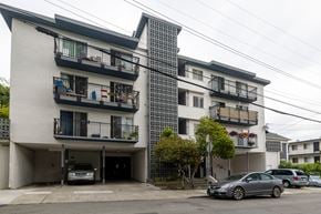 Oakland apartment for rent - A white building with black balconies and a grey car parked in front.