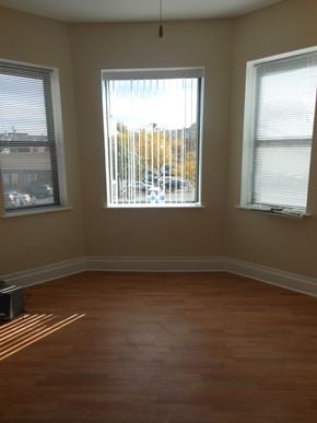 Chicago apartment for rent - an empty room with three windows and a wood floor