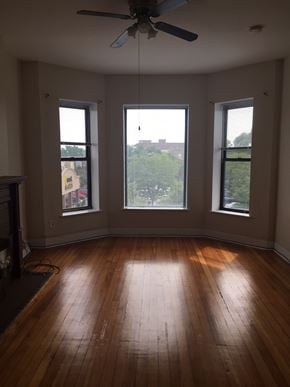 Chicago apartment for rent - an empty living room with wood floors and three windows
