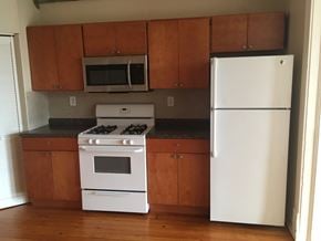 Chicago apartment for rent - an empty kitchen with white appliances and wooden cabinets