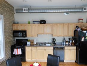Chicago apartment for rent - a small kitchen with black appliances and wooden cabinets