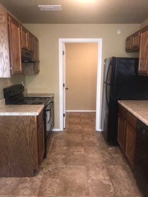 Arkadelphia apartment for rent - A kitchen with a black fridge and wooden cabinets.
