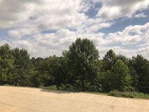 Arkadelphia apartment for rent - A parking lot with trees in the background.