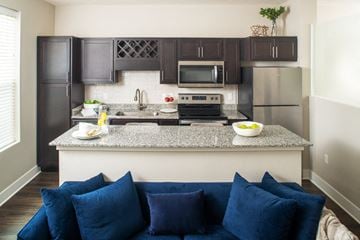 Omaha apartment for rent - a living room with a couch and a kitchen with stainless steel appliances