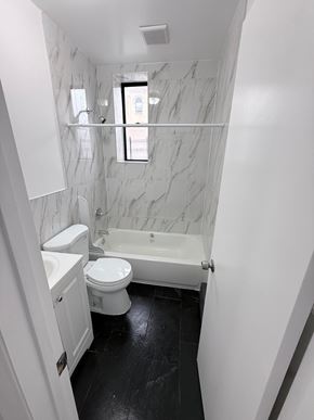 Brooklyn apartment for rent - A white toilet and sink in a bathroom with marble walls.