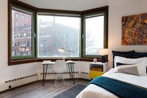 Brooklyn apartment for rent - a bedroom with large windows and a bed and a desk with a chair