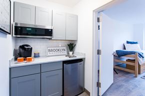 Brooklyn apartment for rent - a kitchen with white cabinets and a sink and a microwave   and a bed
