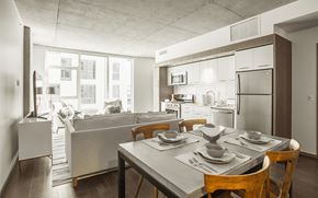 Portland apartment for rent - Dining room and kitchen with stainless steel appliances looking into living room space with white walls at Block 17 Apartments in the Pearl District in Portland, Oregon.