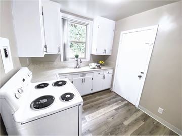 San Francisco apartment for rent - a kitchen with white cabinets and a stove and a window