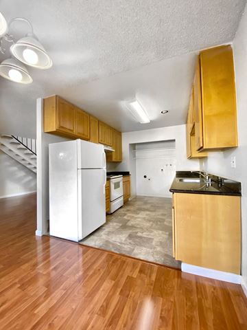 Newark apartment for rent - an empty kitchen with a white refrigerator and wooden cabinets