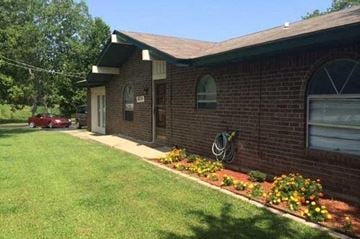 Choctaw house for rent - A red car is parked in front of a brick house.