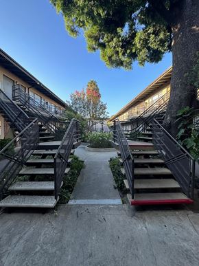 Van Nuys apartment for rent - A set of stairs with a red handrail lead up to a building.