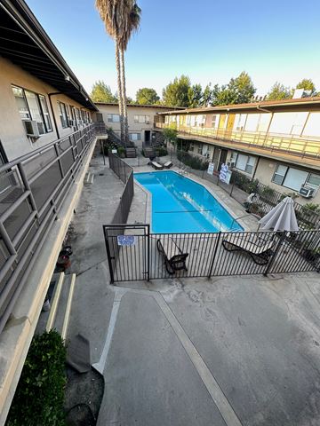 Van Nuys apartment for rent - A pool surrounded by a fence and chairs.
