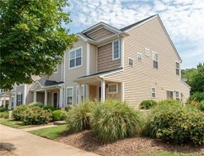 Cornelius house for rent - A house with a brown and beige exterior is surrounded by green shrubbery.